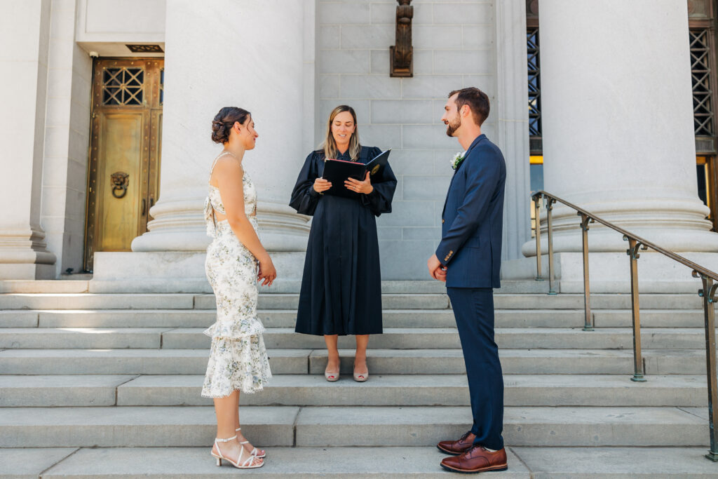 Colorado Elopement Photographer captures bride and groom standing at courthouse with officiant during ceremony