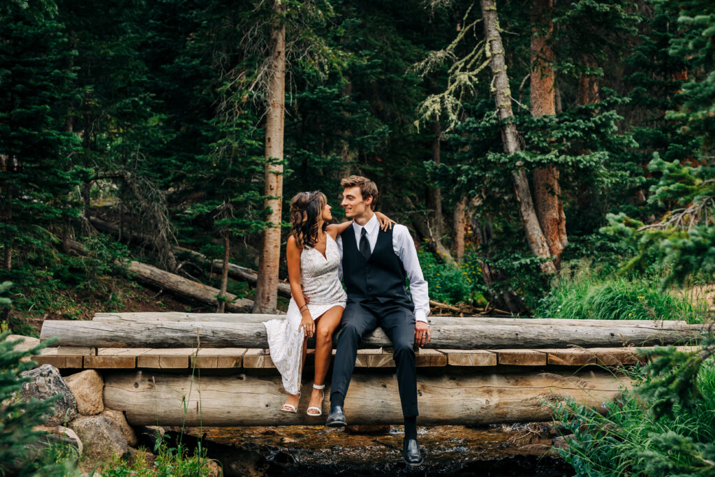 Colorado Elopement Photographer captures bride and groom sitting on log 