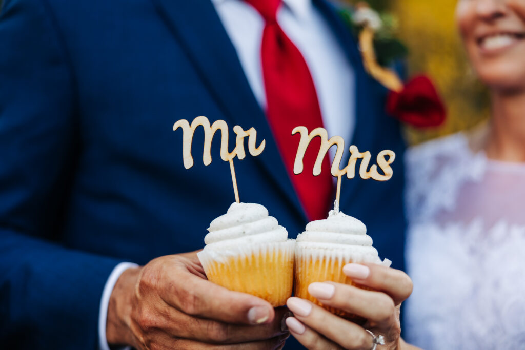 Colorado Elopement Photographer captures bride and groom holding cupcakes with 'mr' and 'mrs' toppers on them