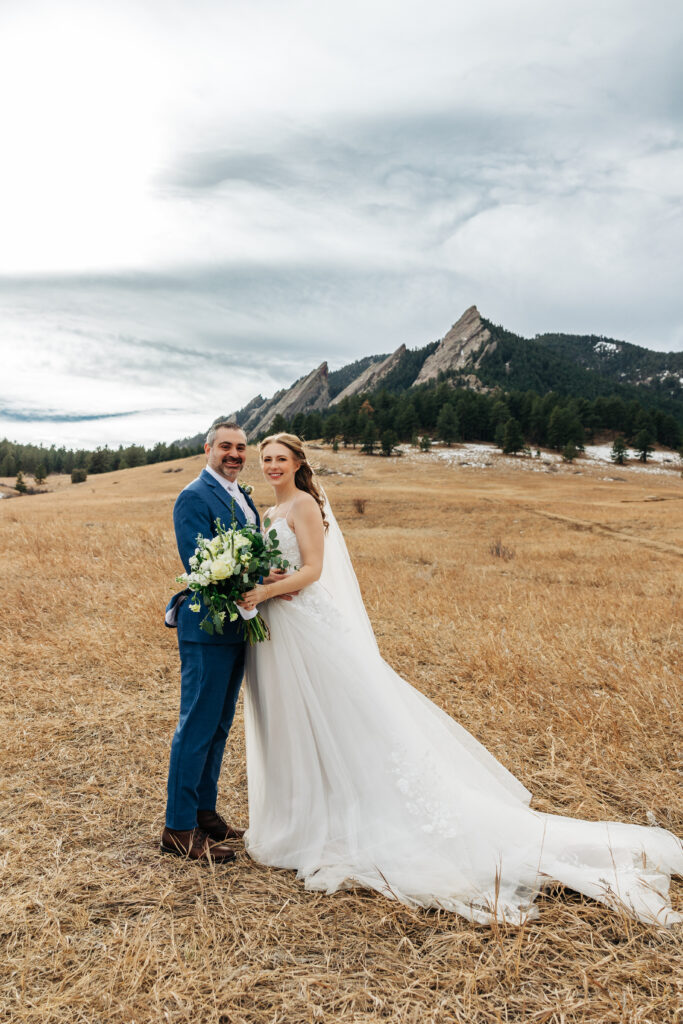 Denver ELopement Photographer captures bride and groom standing in field holding bouquet