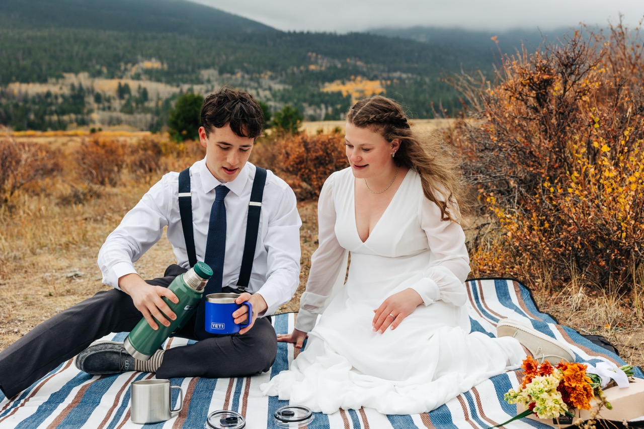 Bride and groom enjoy a thermos of coffee during their post-ceremony picnic after choosing to elope in Boulder.