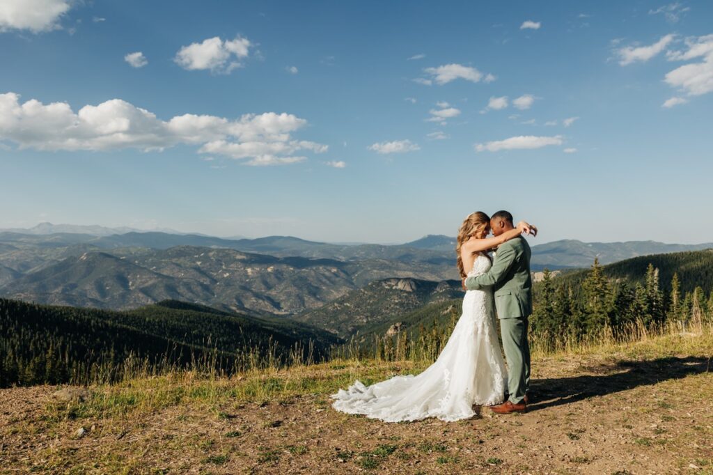 Bride and groom share an emotional embrace with the Rocky Mountains behind them, a romantic moment from their Colorado wedding photos.