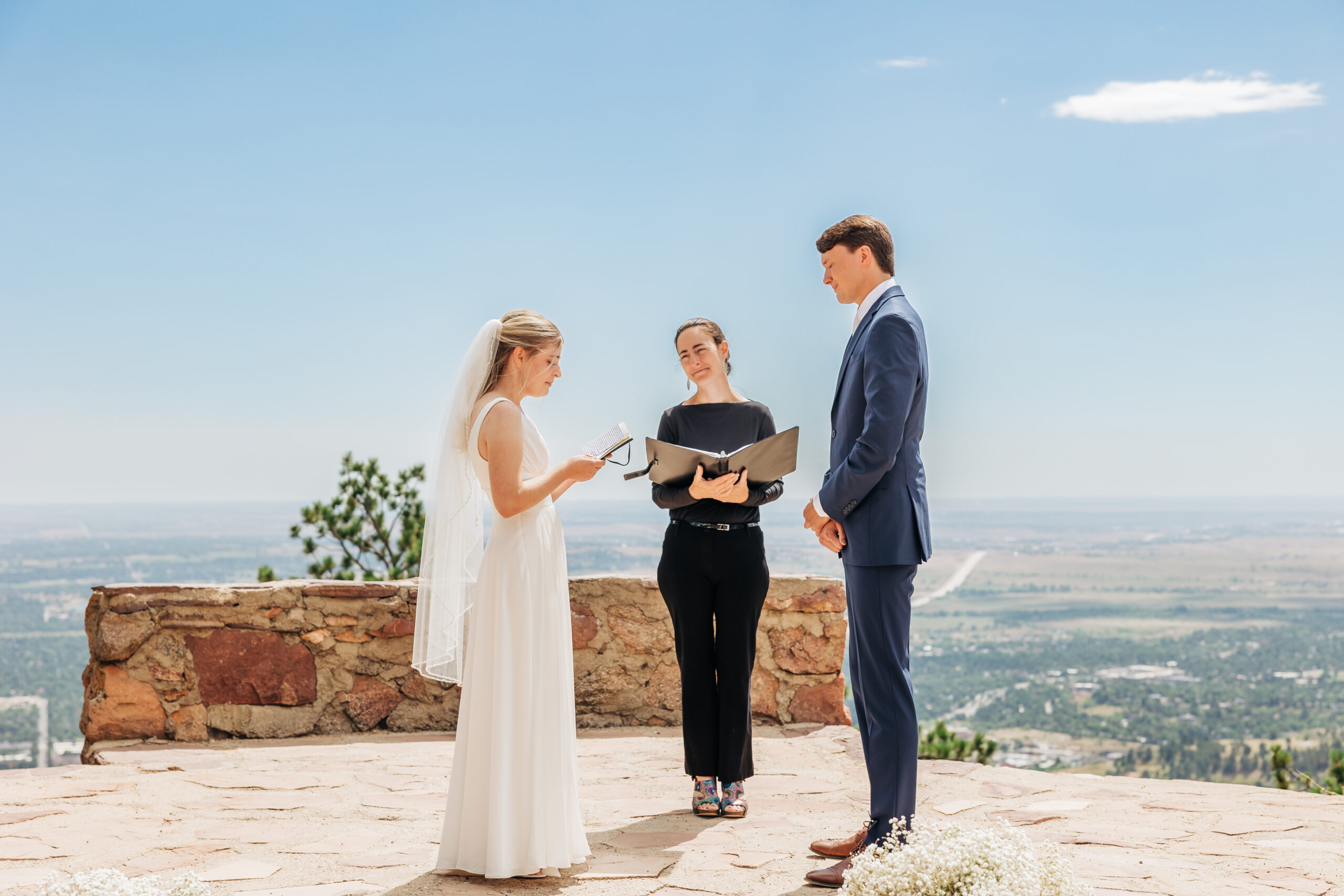 Bride reads personal vows to her groom during a scenic ceremony atop a stone overlook, a perfect moment from their wedding day hike in Colorado.