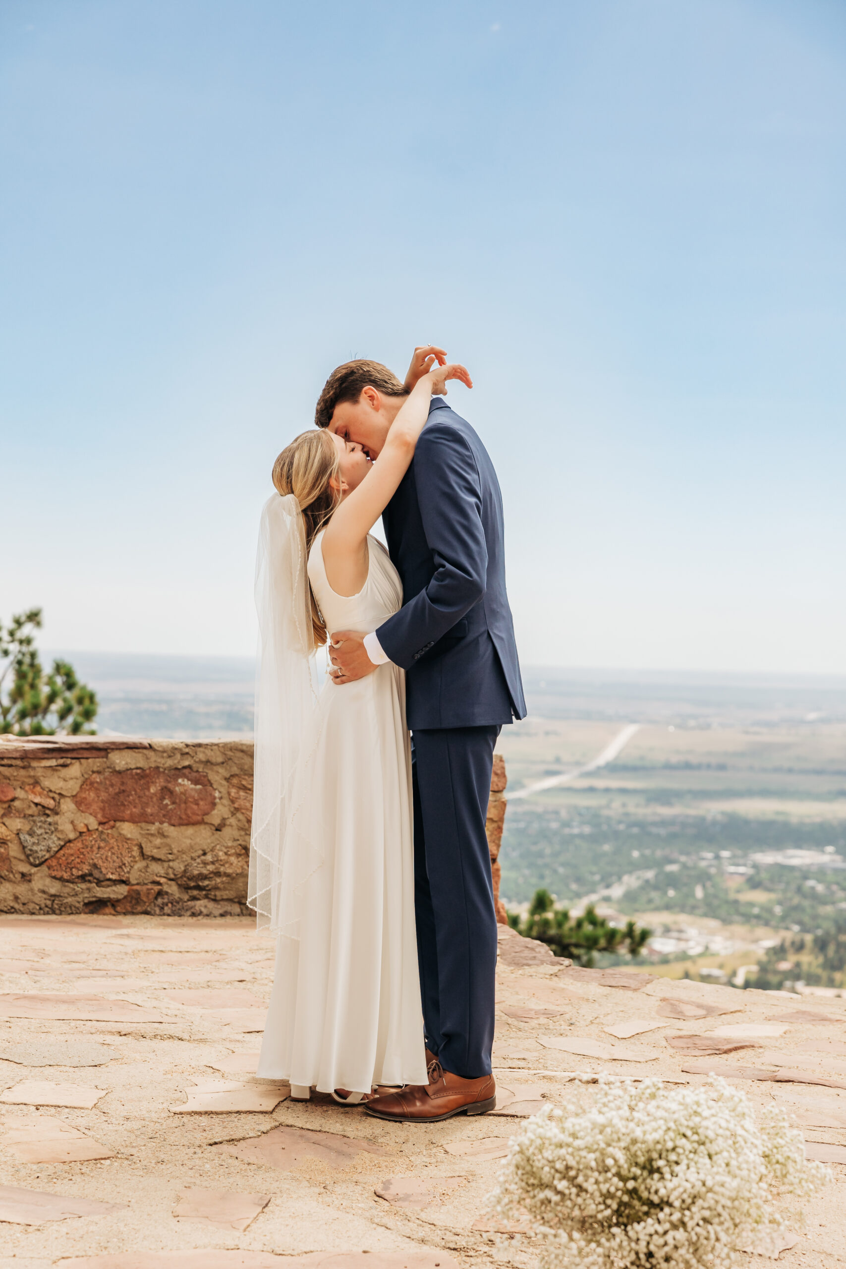 Newlyweds share their first kiss with wide open views behind them, celebrating love and adventure on their unforgettable wedding day hike.