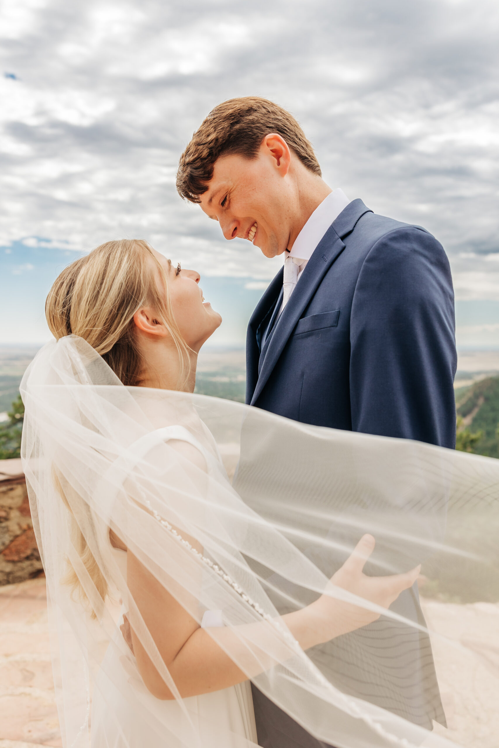 Bride’s veil flows in the breeze as the couple shares a joyful, romantic look—one of many candid moments from their wedding day hike.