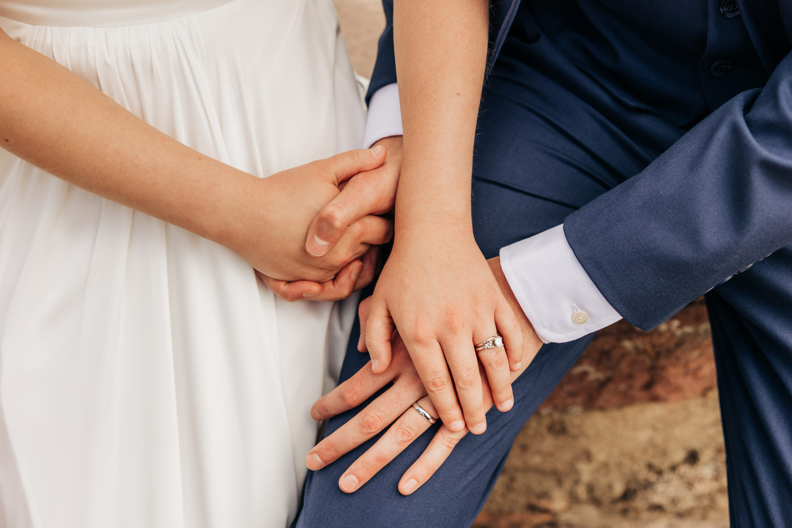 Close-up of the couple’s hands resting together, their rings a symbol of love captured beautifully during their mountain wedding day hike.
