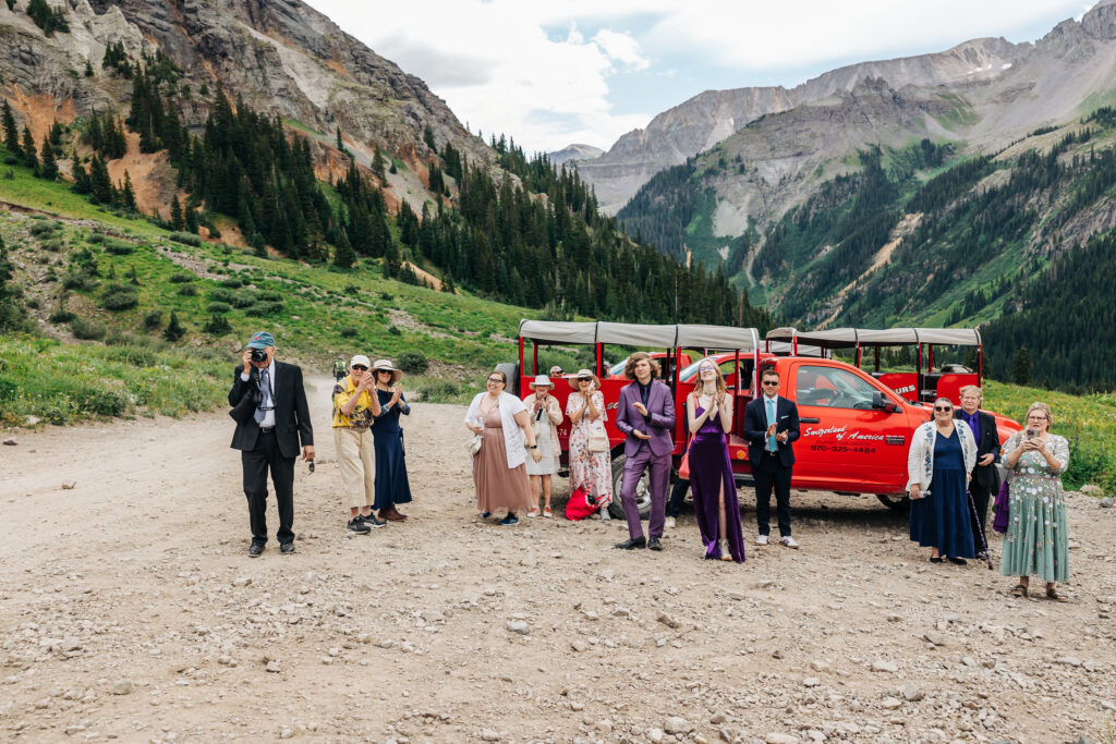 a group of people standing in front of a truck with mountains in the background. They are there for the off-roading elopement