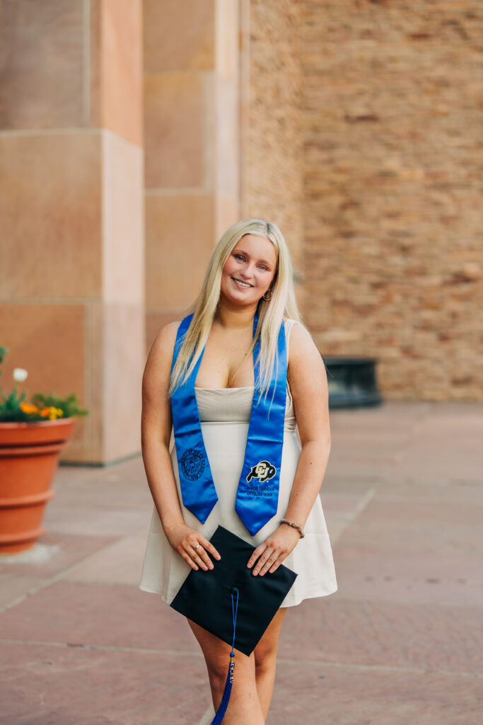 Colorado Senior Photographer captures girl holding cap and smiling outdoors