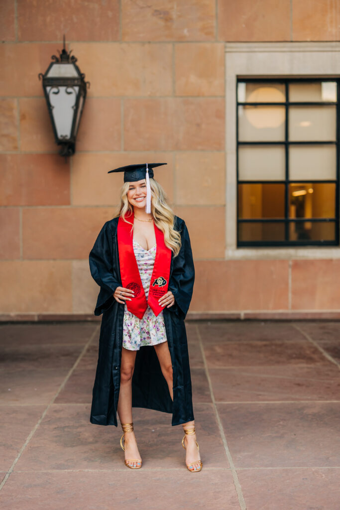 Colorado Senior Photographer captures young woman wearing graduation robes and cap during fun senior session with friends