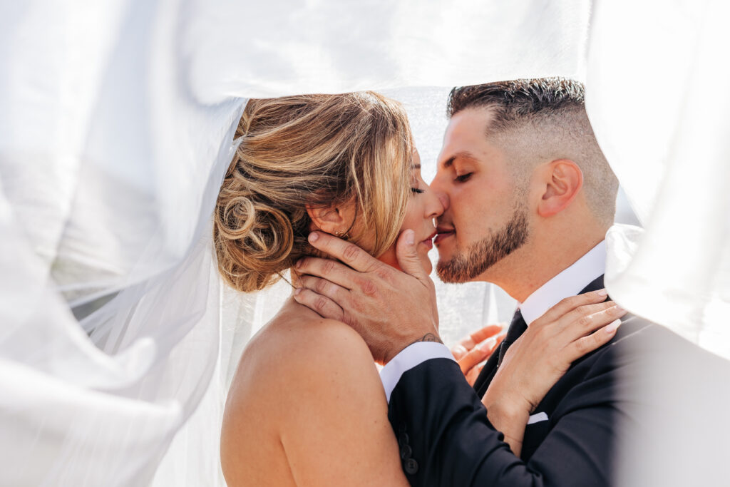 Denver elopement photographer captures bride and groom kissing under veil 