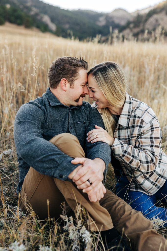 Denver wedding photographer captures couple laughing together while sitting in grass