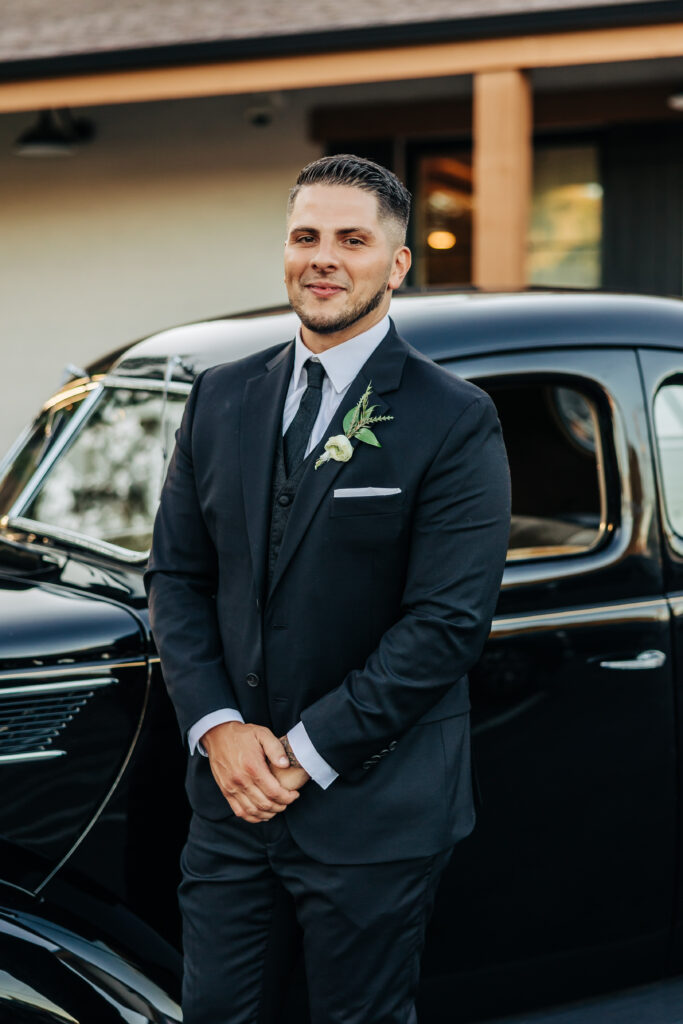 Boulder Wedding Photographer captures groom standing by black car in suit