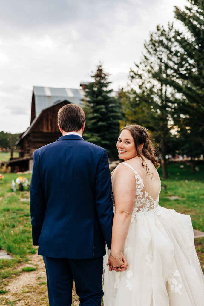 Colorado Wedding Photographer captures bride looking over shoulder with groom walking hand in hand