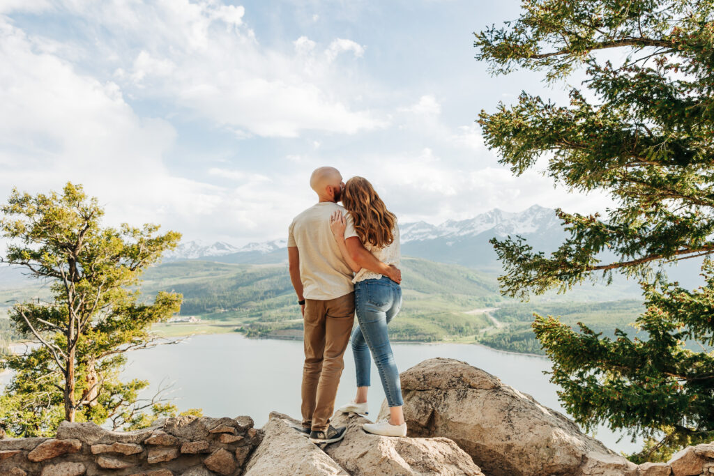 Denver Engagement Photographer captures man and woman standing on boulder looking at view while embracing