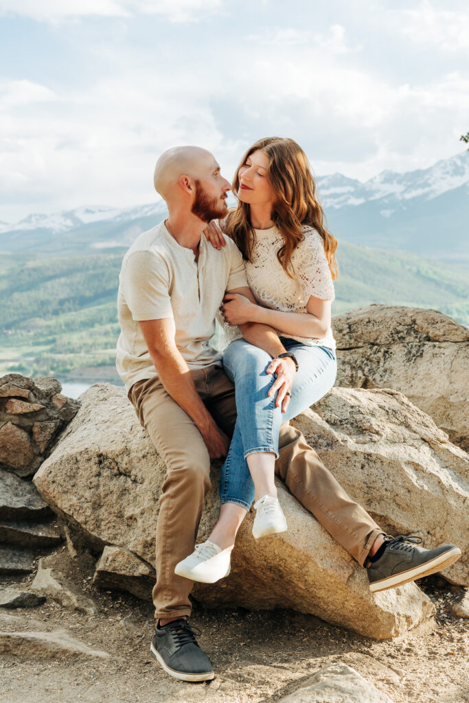 Couple laughing together while sitting together on a rock