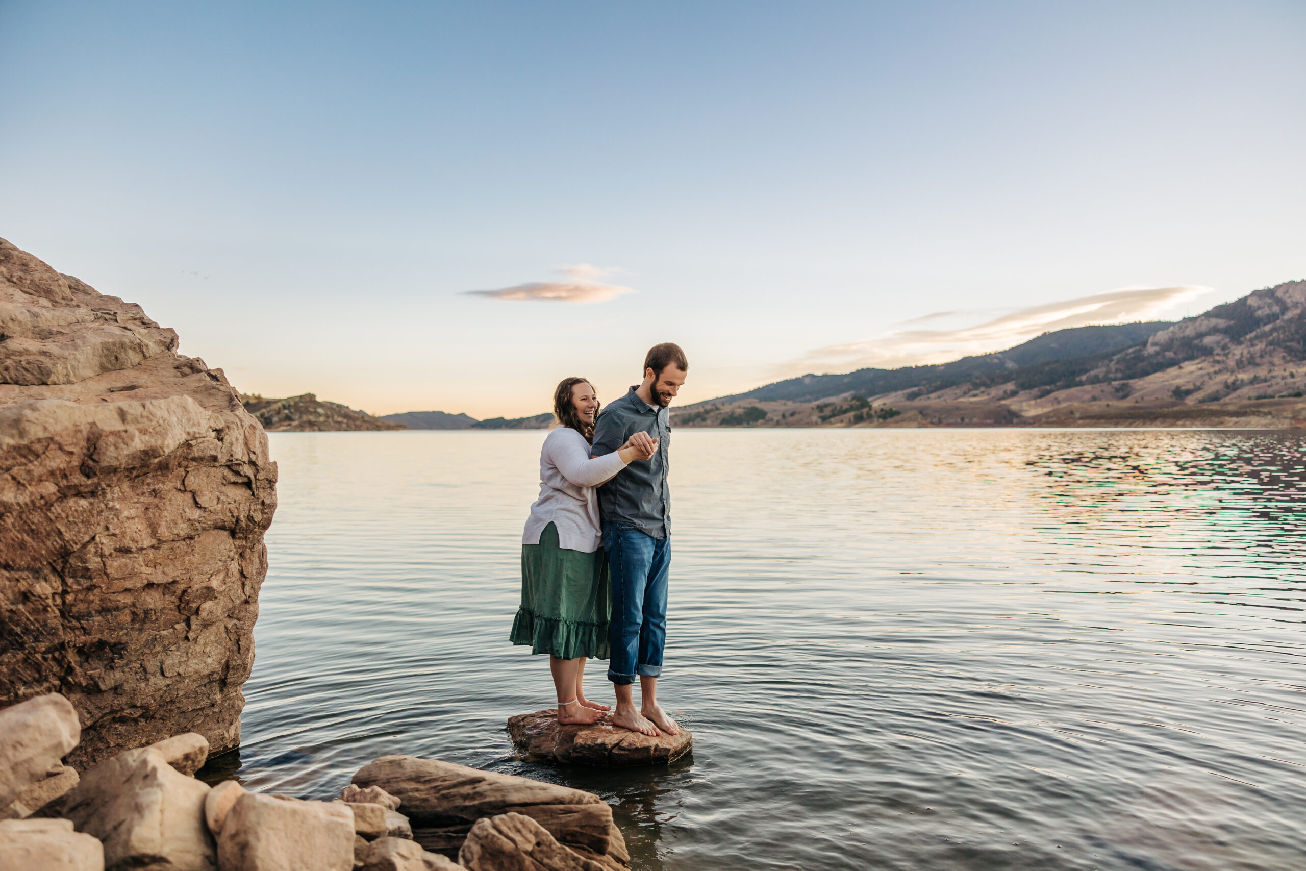Boulder Wedding Photographer captures newly engaged man and woman standing on rock during sunset engagement photos