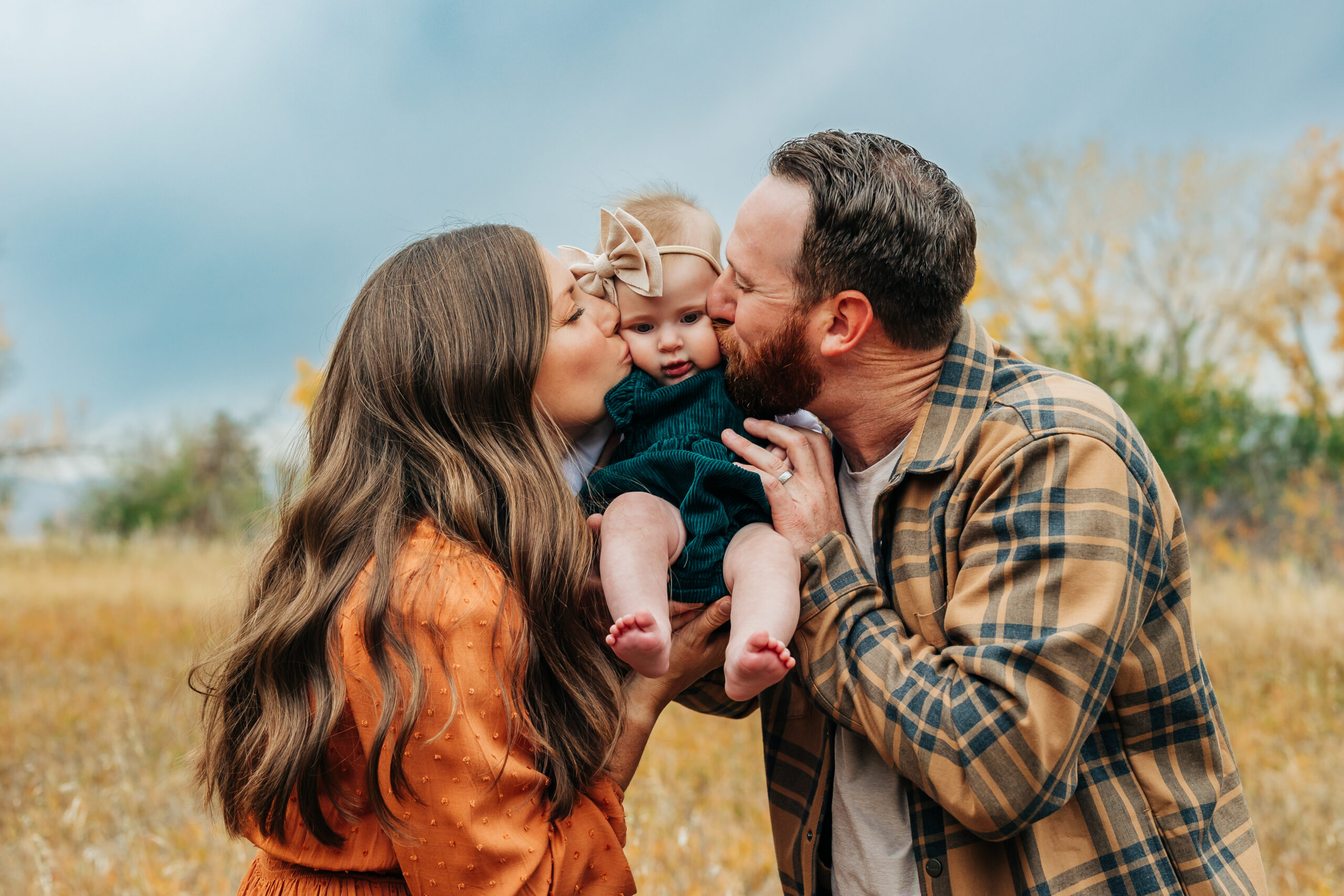 Denver Family Photographer captures mother and father kissing baby's cheeks