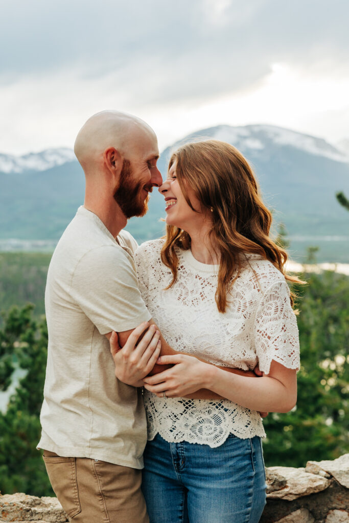 Man and woman embrace and laugh during photos in mountains of Colorado