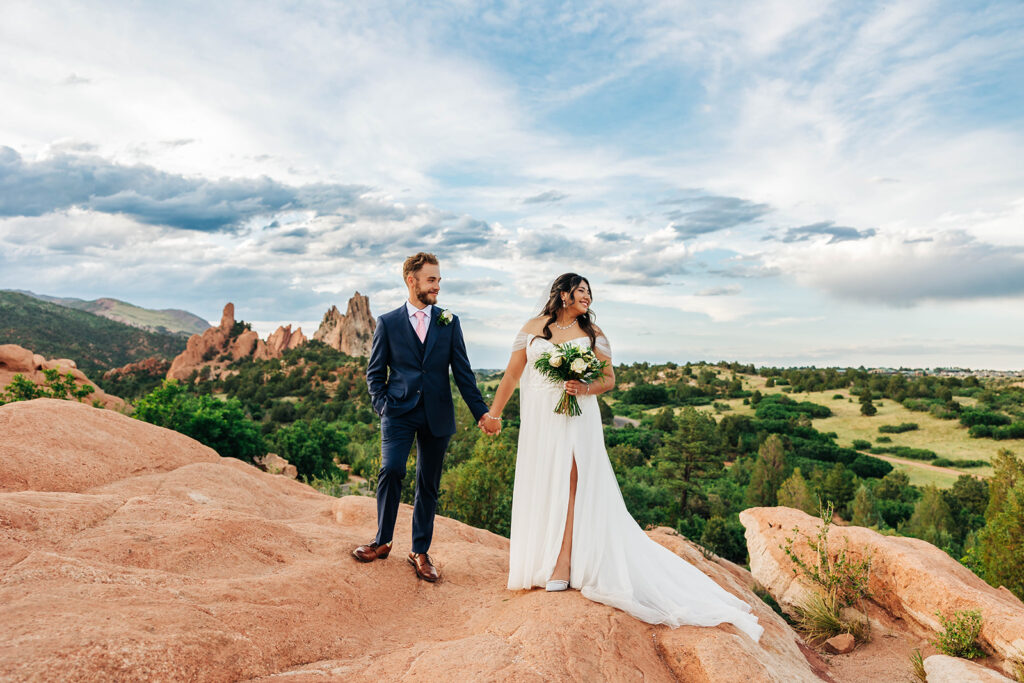 Colorado Elopement Photographer captures bride and groom holding hands on top of red rock after destination elopement