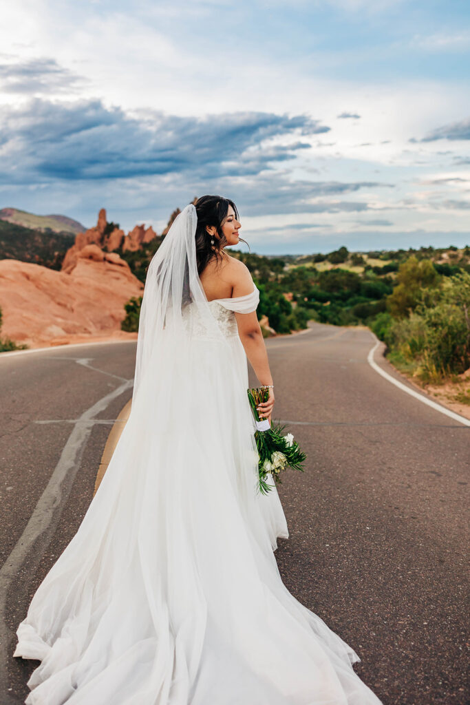 Colorado Elopement Photographer captures bride walking away on road holding bouquet