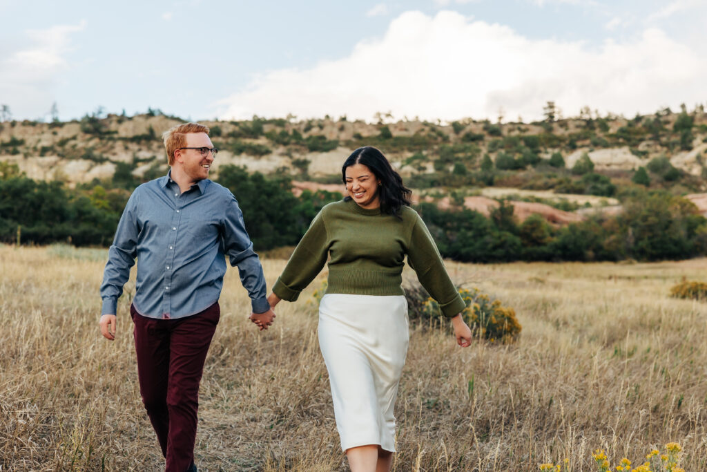 Colorado Elopement Photographer captures man and woman walking hand in hand through grass