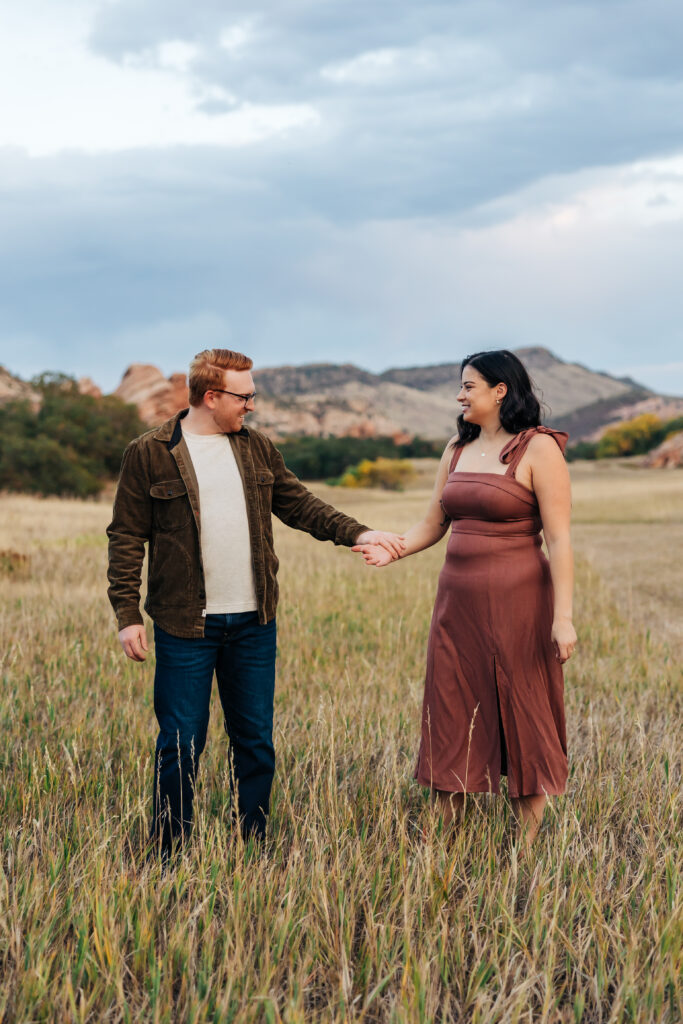 Colorado Elopement Photographer captures woman wearing rust slip dress and man wearing brown jacket during fall engagement photos