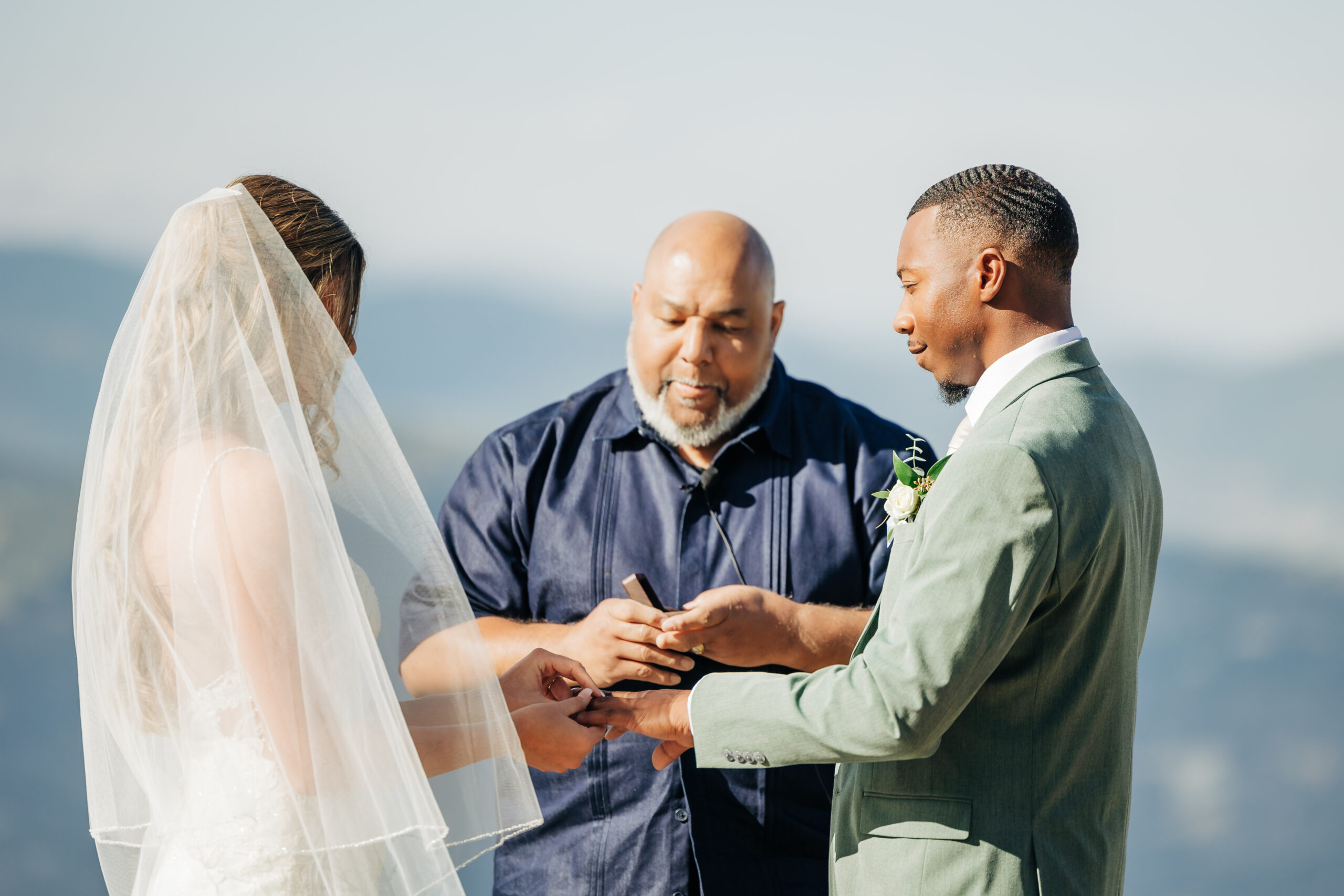 Bride places the wedding ring on her groom’s finger during a heartfelt Colorado mountain wedding ceremony, with the officiant guiding their vows.