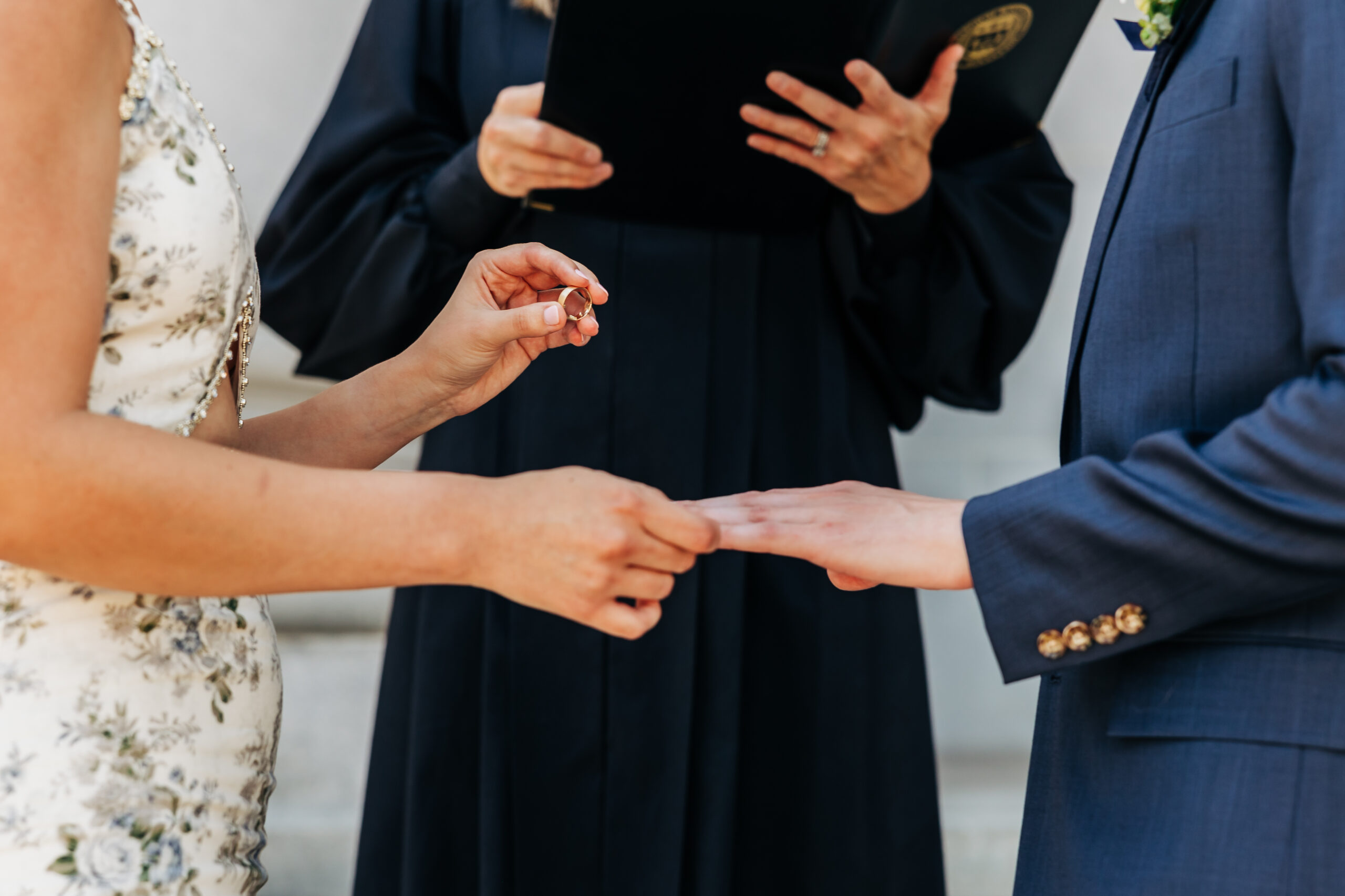 A close-up moment of the bride placing a ring on her partner’s finger during a simple ceremony to save money for their Colorado elopement.