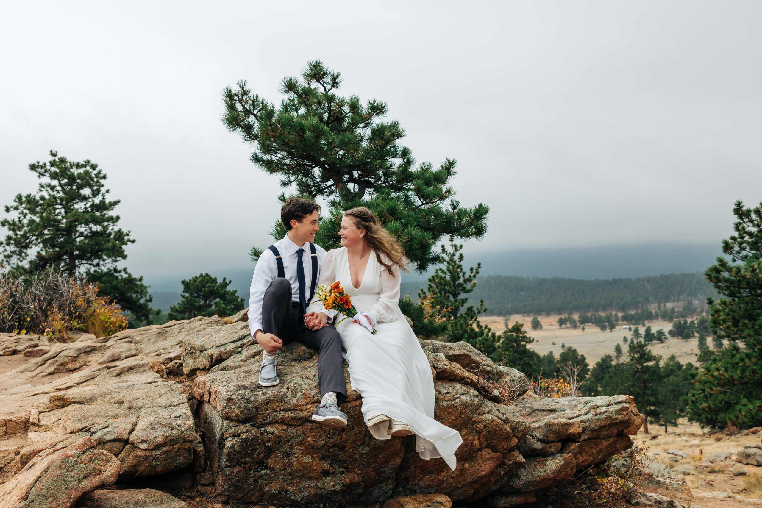Newlyweds relax on a rocky overlook, soaking in the views after deciding to elope in Boulder.
