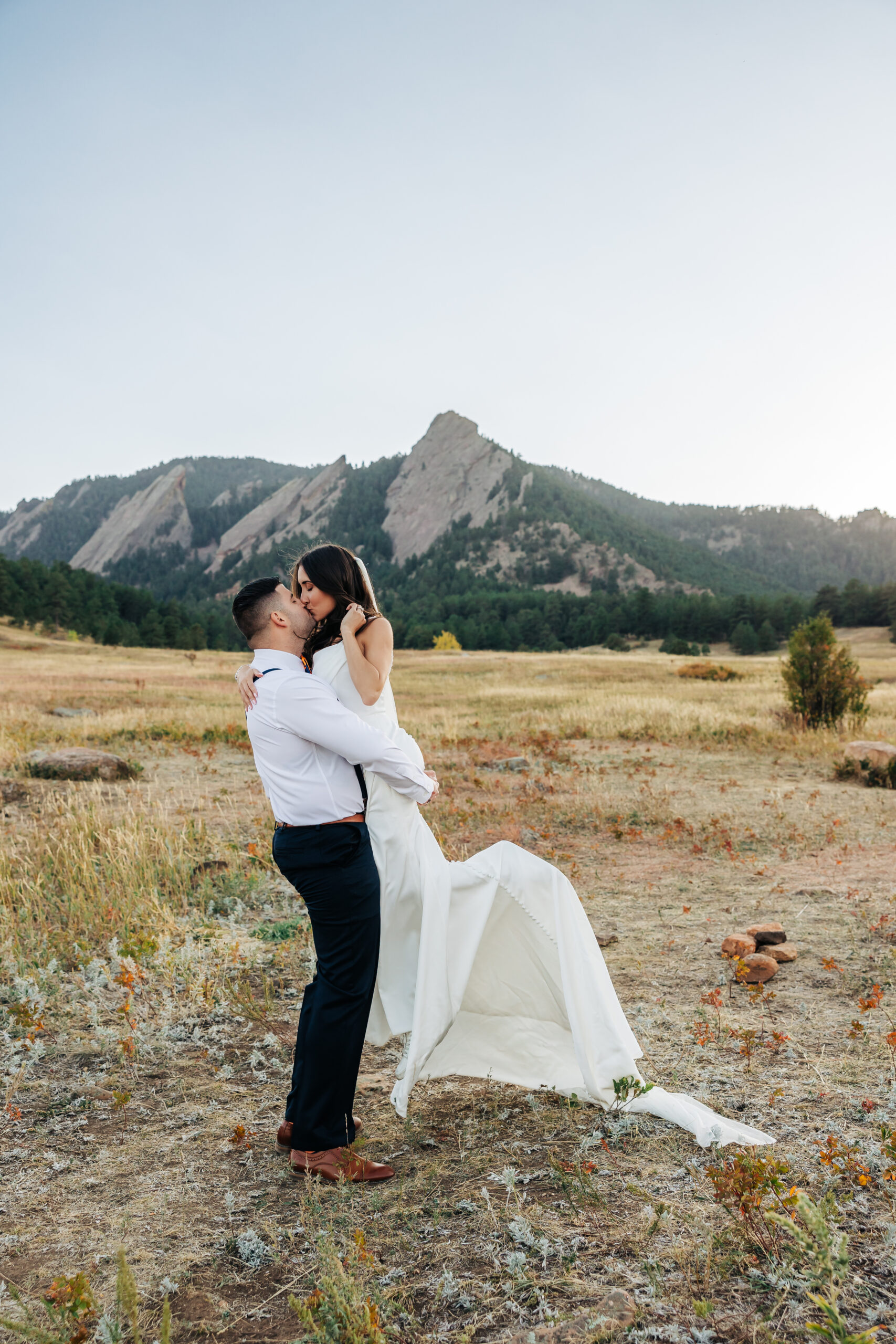 Romantic kiss as the groom lifts the bride with the Flatirons rising behind them — a stunning highlight of our Colorado elopement packages.