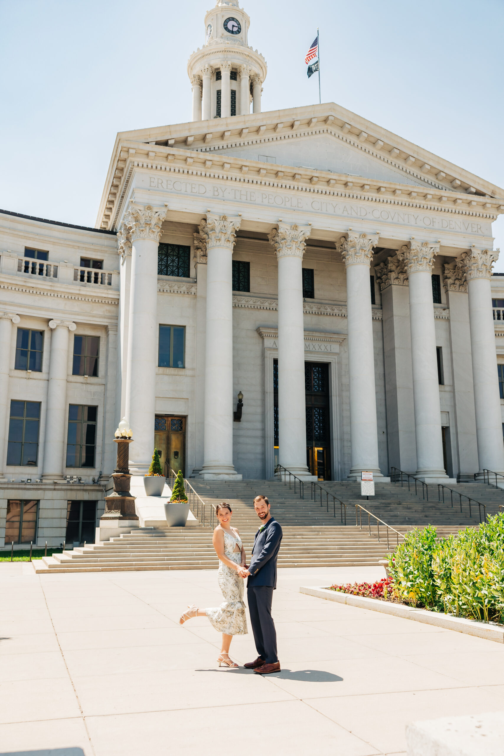 Couple celebrates in front of Denver’s City and County Building, a stunning and budget-friendly venue to save money for your Colorado elopement.