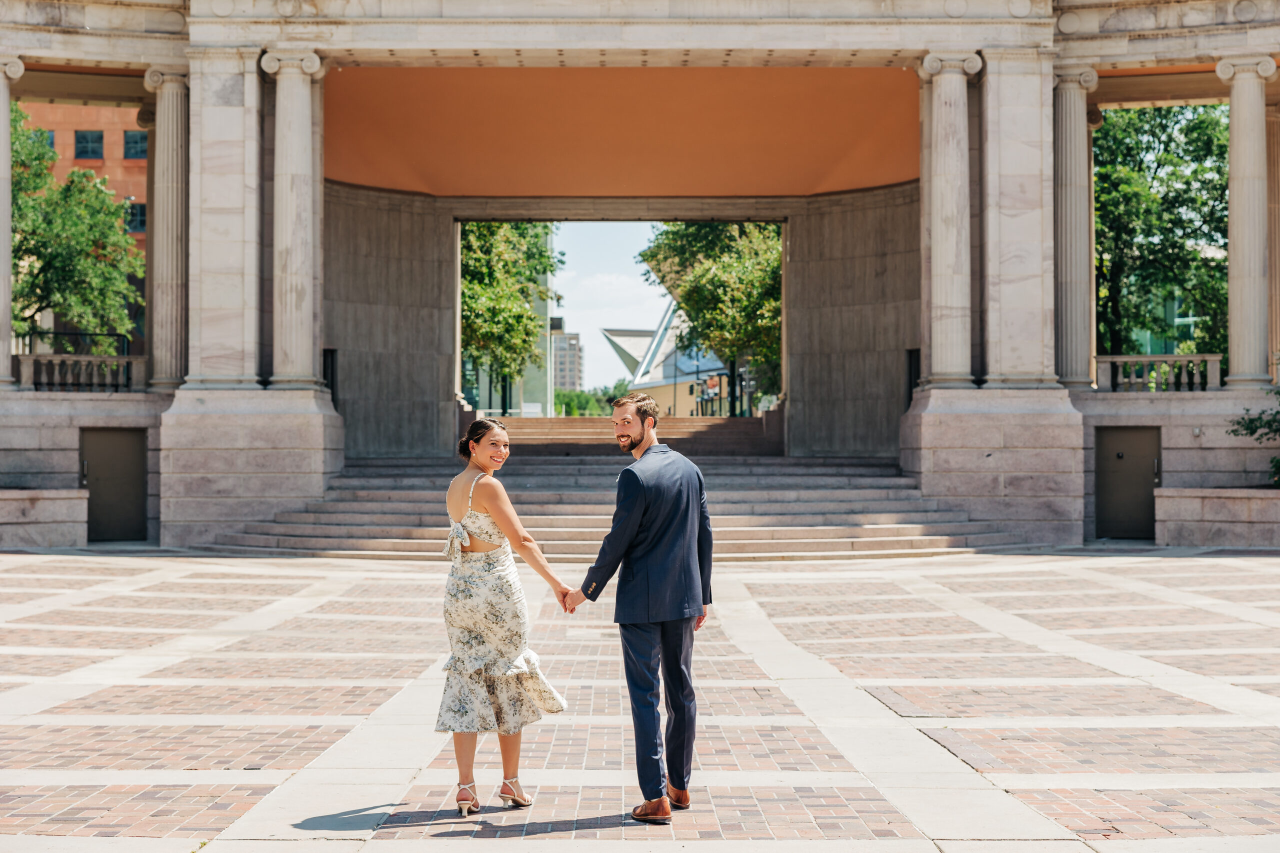 Newlyweds stroll hand in hand through Denver’s Civic Center Park, proving you can save money for your Colorado elopement without skimping on style.