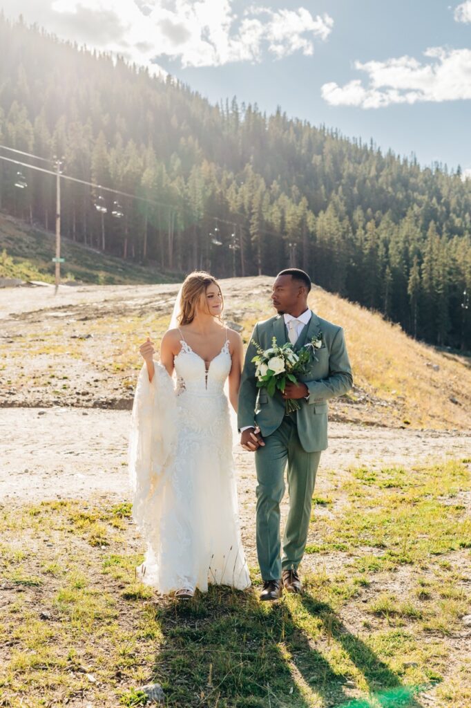 Bride and groom walk side by side near their Colorado mountain wedding venue, smiling and soaking in the day.