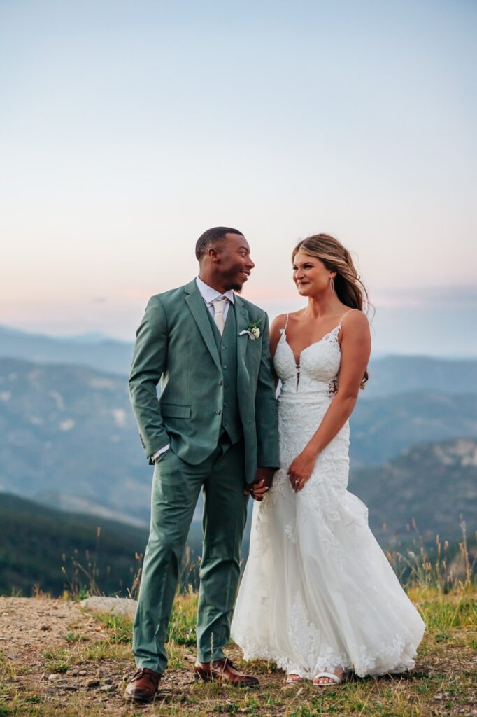Bride and groom exchange loving looks as the sun sets over their Colorado mountain wedding celebration.