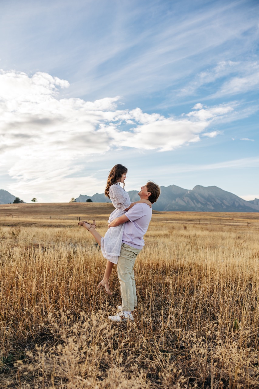 man lifting woman in the air in golden field